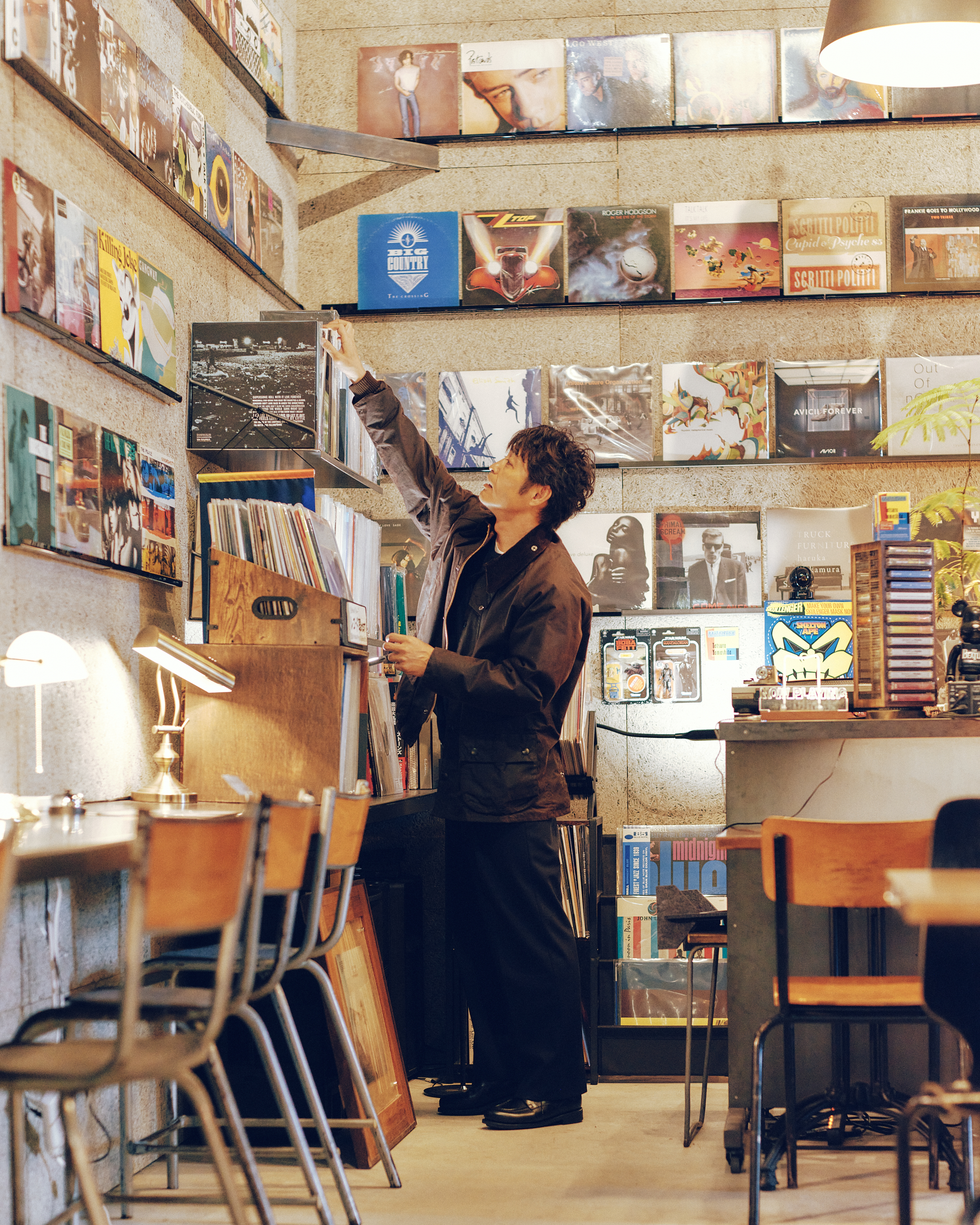 レコード店「ボイラーレコード」でBarbourのブラックのジャケットを着用した男性がレコードを選んでいる様子