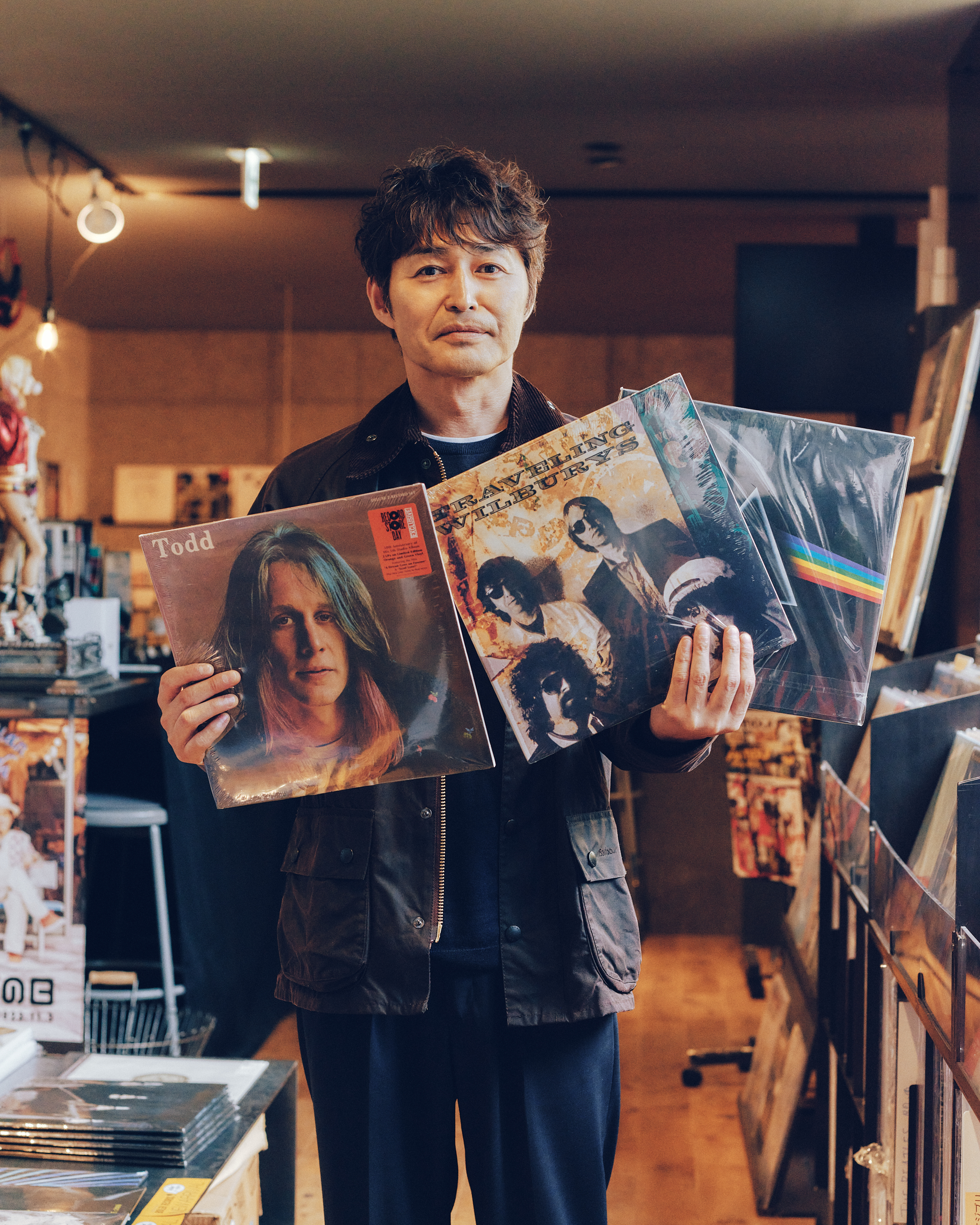 レコード店「ボイラーレコード」でBarbourのブラックのジャケットを着用した男性がレコードを選んでいる様子